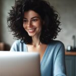 Une femme européenne souriante et concentrée devant son ordinateur portable.